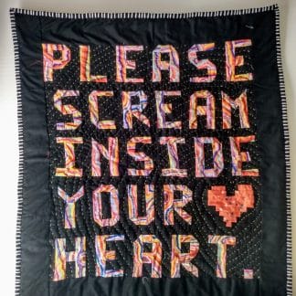 Black quilt reads "please scream inside your heart."